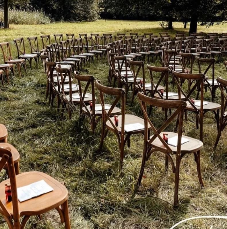 Rijen houten stoelen in een grasveld, klaar voor een evenement.